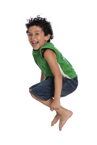 boy with curly hair in green top jumping up in air