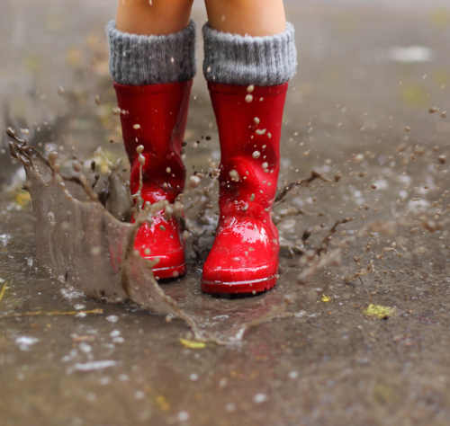 red rain boots jumping in puddle