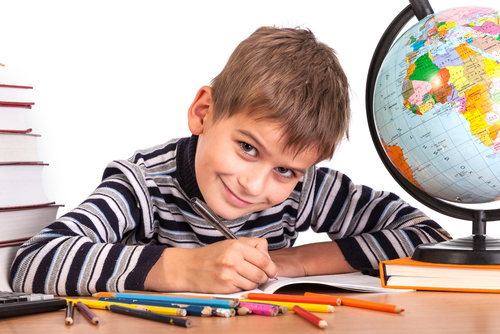 A boy who is writing and smiling.