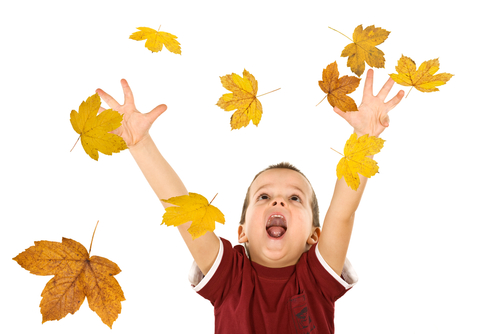 child throwing leaves in air