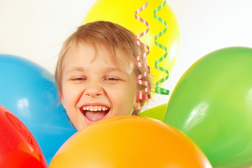Smiling boy surrounded by balloons.