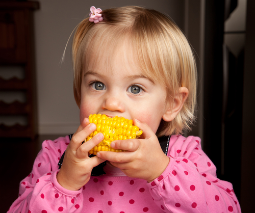 a girl eating sweetcorn