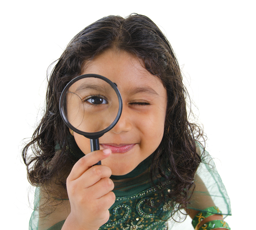 girl looks thorugh magnifying glass