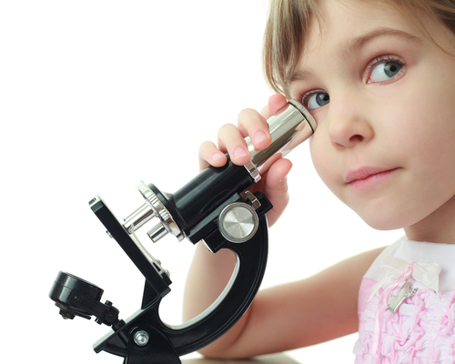 girl looking down a microscope