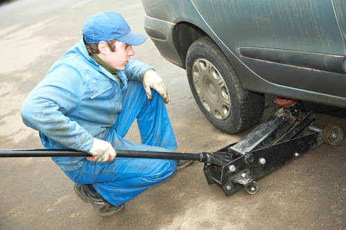 mechanic using a jack to lift a car