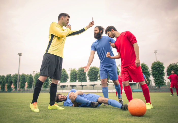 Injured footballer and another footballer receiving a red card